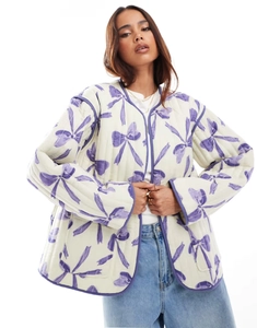 Close-up of women's quilted jacket featuring cute purple bow prints and a round neck