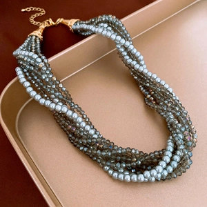 Macro view of multi-layered pearl and crystal necklace with gold hardware in tray