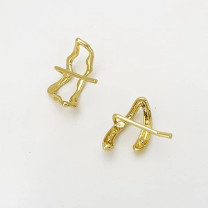 Macro detail of golden U-shaped hair clip with abstract wavy metallic design on white back