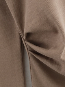 Macro detail of brown knit fabric showing soft texture and premium stitching seams