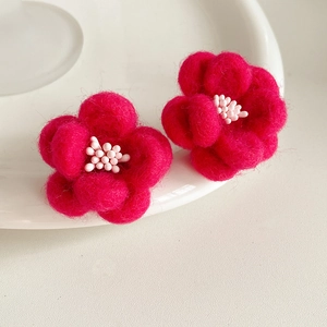 Gros plan détaillé de boucles d'oreilles fleurs en feutre rouge rose faites à la main
