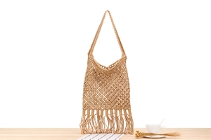 Detail of handmade macramé beach bag with diamond mesh patterns and long fringes