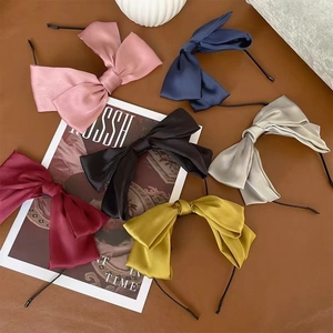 Elegant satin bow hairpins in six colors including pink, navy, and wine red displayed on brown