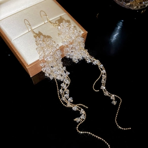Macro detail of long crystal beaded fringe earrings with golden hooks on a gold jewelry box