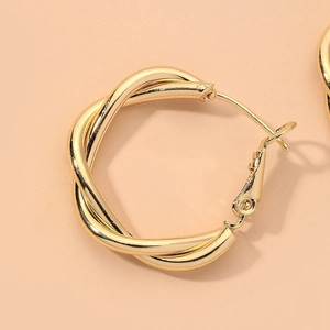 Detail of twisted champagne gold hoop earrings with polished metal finish and clasp