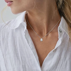 Elegant pear-shaped emerald zircon pendant necklace with silver chain on white linen