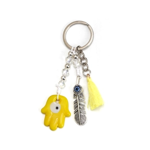 Macro shot of Hamsa hand charm with yellow tassel and silver feather on keychain