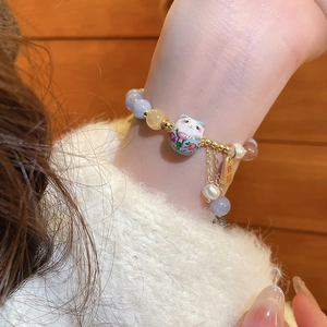 Close-up of Lucky Cat beaded bracelet with purple beads and golden Fu charm details