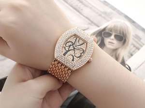 Rose gold tonneau watch with crystals and mesh strap shown on a model wrist