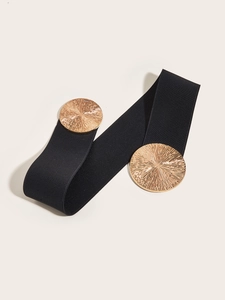 Detail of black wide elastic belt featuring large round gold metal buckles with sunburst texture