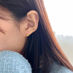 Close-up of minimalist gold heart-shaped zircon stud earrings worn by a female model