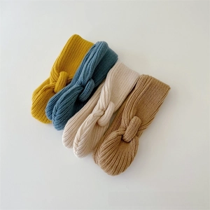 Detail of four knit baby headbands with knot design in yellow blue beige and khaki