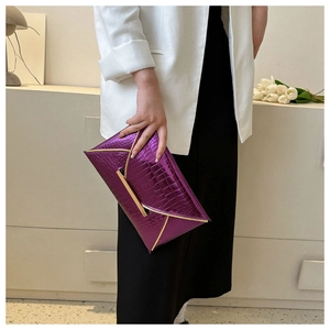 Detail view of purple faux crocodile envelope clutch with gold metal trim and bar lock