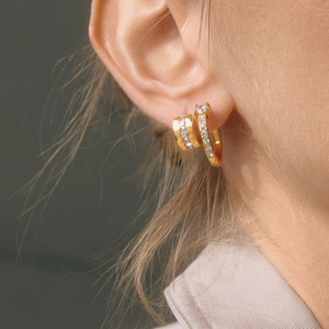 Close-up of gold stainless steel hoop earrings with sparkling cubic zirconia on a model