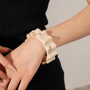 Detail of wide wavy resin bangle with cream and brown amber marble texture on wrist