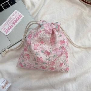 Detailed texture of pink floral cotton drawstring storage pouch on a white linen background