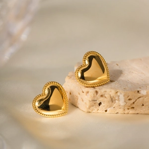 18K gold plated stainless steel heart stud earrings with beaded edge on stone surface