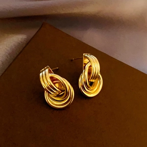 Detail of gold multi-layered geometric hoop earrings with a twisted spiral design
