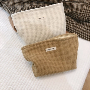 Close-up detail of retro woven textured makeup bags in camel and off-white colors