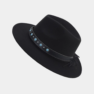 Detalle de sombrero fedora negro con gema turquesa y banda de tachuelas de plata