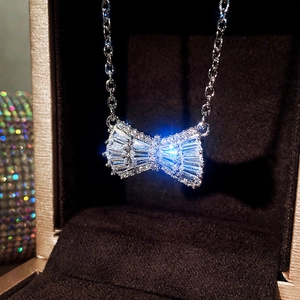 Close-up of a silver bow necklace with sparkling zircons inside a luxury jewelry box