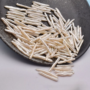 Macro detail of natural stick-shaped Baroque freshwater pearls in a dark display tray