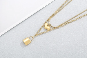 Detail of gold double-layered heart and padlock pendant necklace on neutral background