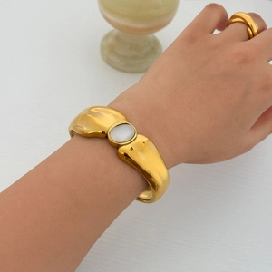 Detail of 18k gold plated open bangle with white oval stone and matching minimalist ring