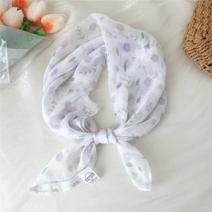 Close-up of floral print silk scarf featuring purple flowers and light fabric texture