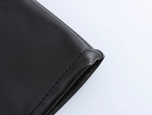 Close-up detail of black leather texture and premium stitching on a halter dress