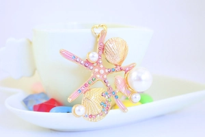 Close-up of golden starfish and shell keychain with colorful gems and white pearls