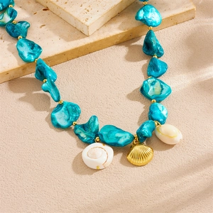 Bohemian stainless steel jewelry set with blue stones and gold shell pendants on a stone base
