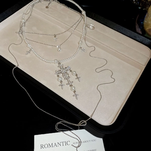 Close-up of pearl and crystal cross layered necklace on a jewelry display tray
