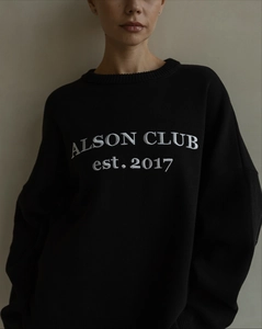 Close-up of ALSON CLUB white embroidery on a premium black knitted crewneck sweater
