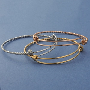 Detailed view of twisted cable metal bangles in silver, gold, and rose gold finishes