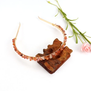Detailed macro view of handmade gold wire-wrapped orange natural crystal headband on wood