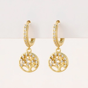 Detail of gold huggie earrings with a sparkling zircon encrusted Tree of Life pendant