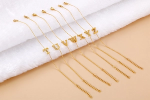 Close-up of golden letter pendants T-Z with rhinestones on delicate adjustable chain