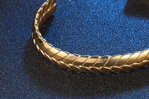 Primer plano del brazalete de acero dorado con textura de espiga en fondo azul