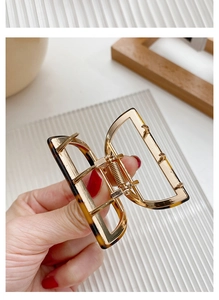Detail of tortoise shell hair claw clip with golden alloy frame and strong metal spring