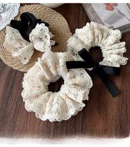 Flat lay of vintage cream lace bow hair scrunchies and accessories on a wooden desk