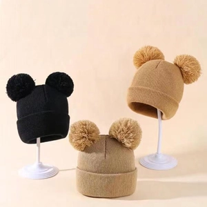 Close-up of double pom-pom knit hats for kids with flexible ribbed cuffs in black and beige