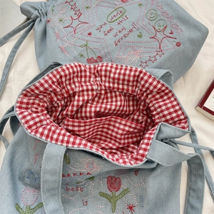Macro shot of denim tote bag with colorful embroidery and red checkered lining