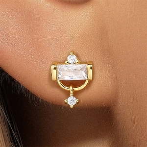 Close-up of golden geometric stud earring with rectangular zircon and small diamonds