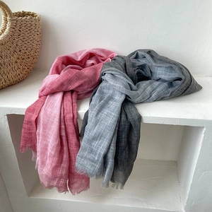 Detail of pink and grey gradient cotton linen scarves with fringe on a white rack