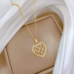 Détail macro du pendentif coeur ajouré doré serti de zircons sur soie blanche