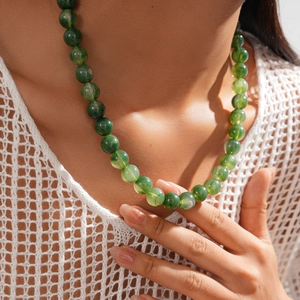 Detail of model wearing green acrylic beaded necklace with vintage marble texture beads