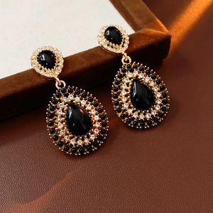 Gros plan de boucles d'oreilles vintage dorées avec pierres noires et strass brillants