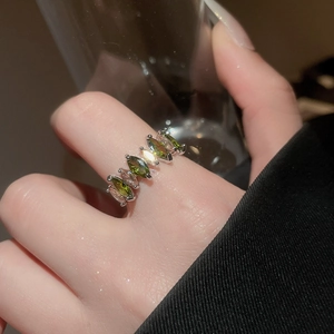 Détail de bague argentée avec oxydes de zirconium vert et clair de taille marquise au doigt
