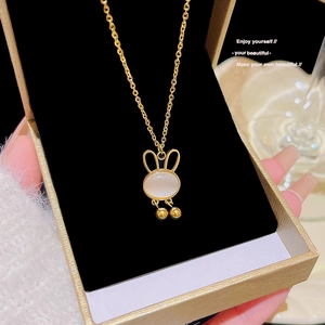 Close-up of golden titanium necklace with a rabbit pendant featuring white opal stone